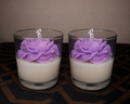 Two glass candles with purple floral designs on a dark surface.