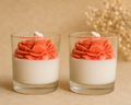 Two glass containers with coral flower-shaped candles on a beige background