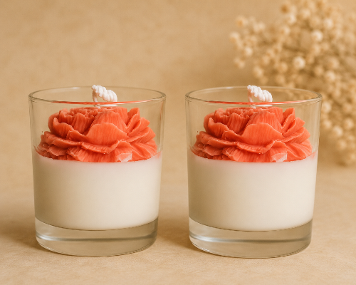 Two glass containers with coral flower-shaped candles on a beige background
