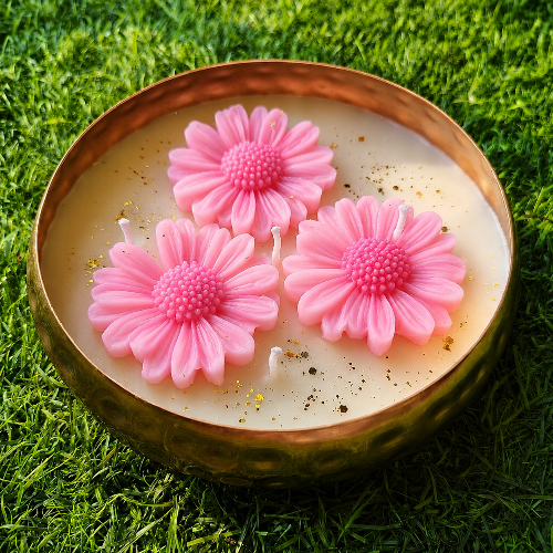 Candle with pink flower-shaped candles on a grassy background