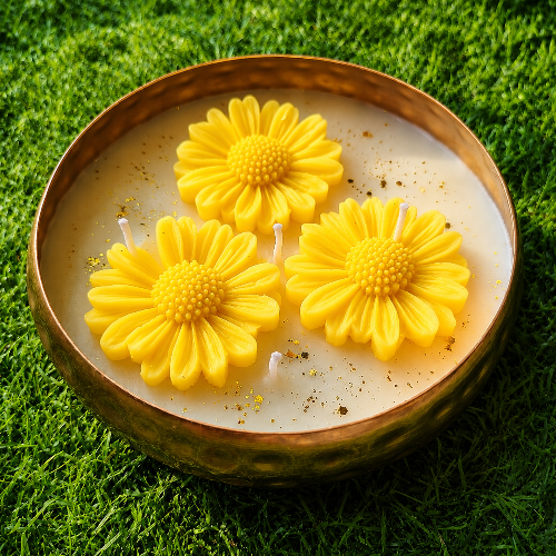 Candle with yellow flower-shaped wax elements on a grass background