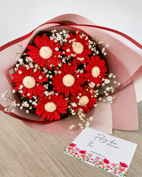 Bouquet of red and white flowers with a card on a wooden surface