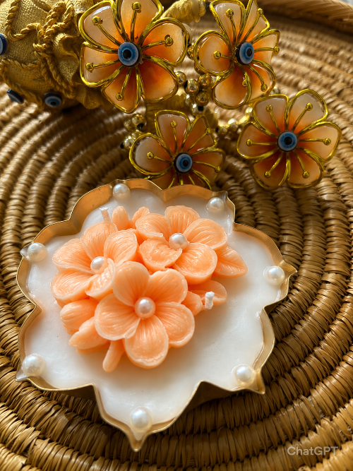 Decorative flower-shaped objects with gold and peach colors on a woven surface.
