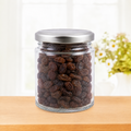 Glass jar with metal lid filled with raisins on a wooden surface with a blurred background
