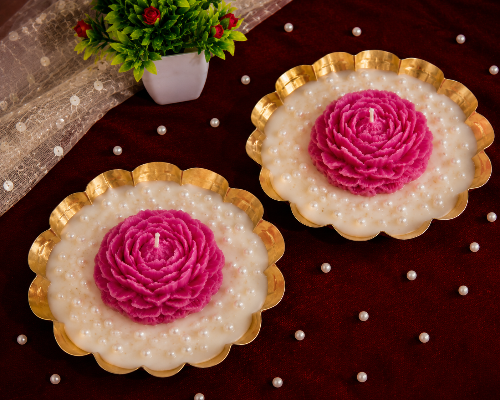 Two decorative candles with pink flower designs on a dark surface.