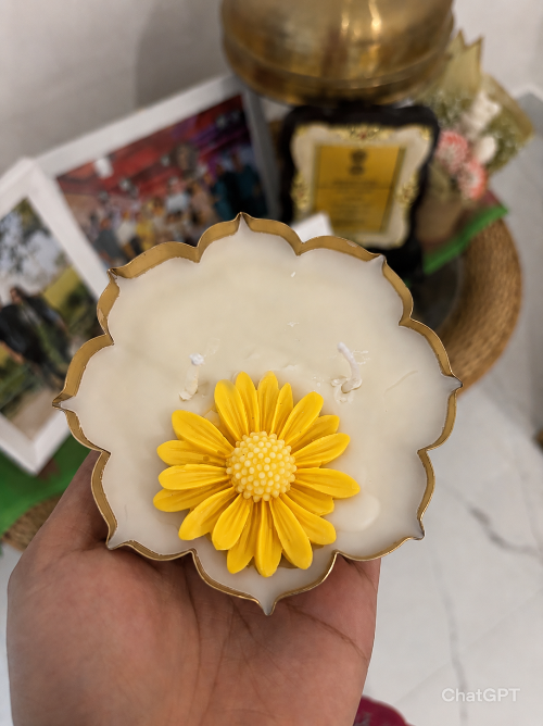 Decorative cookie with a yellow flower design held by a hand, with a blurred background.
